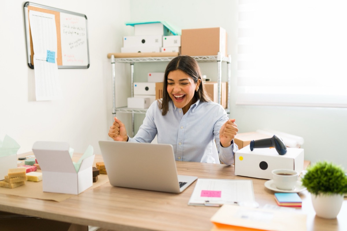 Mujer celebrando frente a su laptop en su oficina